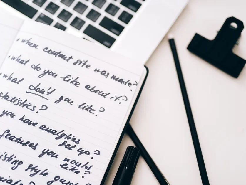 Carnet de notes manuscrites ouvert à côté d’un ordinateur portable